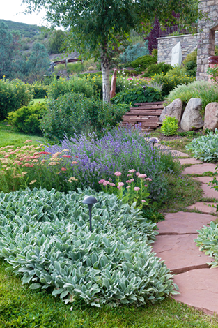 Photo of flowers and dcorative shrubs, sandstone walkway, lighting, and marble sculpture